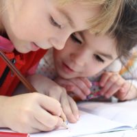 girls-on-desk-looking-at-notebook-159823